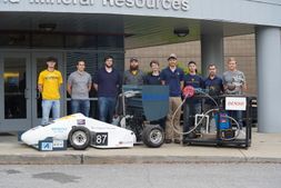 The Mountaineer Racing Powertrain team Team pose with the 2017 Formula SAE race car and the engine dynamometer built with funds donated by DENSO North America Foundation