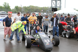 Cameron Sutton exits the dynamics area after successfully completing the 22 km Endurance Race at the 2015 Formula SAE® Michigan Competition flanked by the rest of the WVU team.