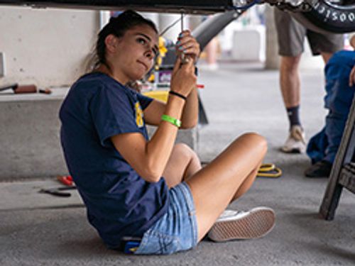 Isabella Kudyba tightens the screws that mount the undertray of as the team prepares for tech inspection at the 2021 FSAE competition.
